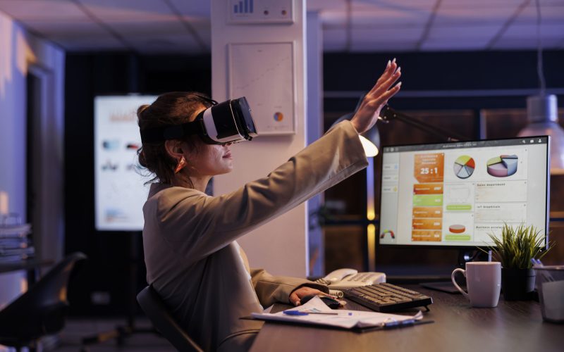 Executive manager wearing virtual reality headset, analyzing financial growth report using hologram in startup office. Businesswoman working late at night at company startegy. Technology concept